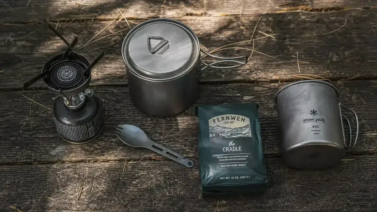 Cast iron skillet with eggs and bacon on a camp stove, forest background